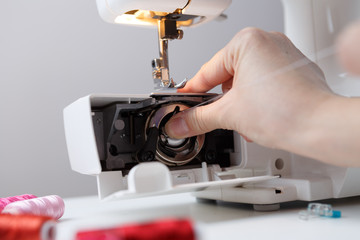 Arm inserts bobbin in sewing-machine