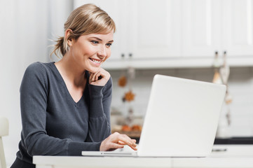 Cute smiling woman sitting in her room and using laptop computer