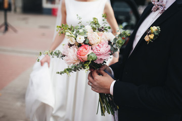 The groom keeps a wedding bouquet for bride