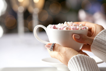 Female hand holding a cup of hot chocolate with marshmallows.