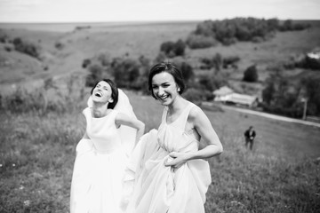 The bride with bridesmaid walking along field
