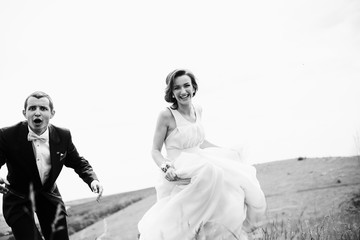 Fototapeta na wymiar The bridesmaid and groomsman running along field