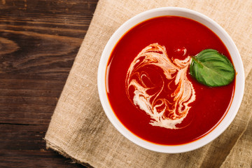 Homemade tomato soup on wooden table, top view