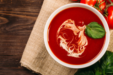 Homemade tomato soup on wooden table, top view
