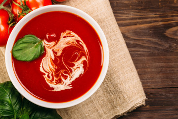 Homemade tomato soup on wooden table, top view