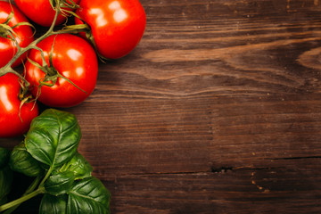 Italian food background with vine tomatoes and basil leaves Ingredients on dark wooden rustic background Copy space Top view