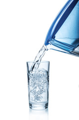 Pouring water from filter pitcher into glass on white background