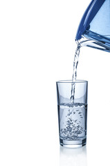 Pouring water from filter pitcher in glass on white background
