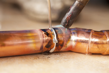 soldering copper pipes with tin and torsh - obrazy, fototapety, plakaty