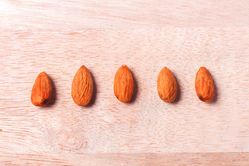 Almonds in brown bowl on wooden background