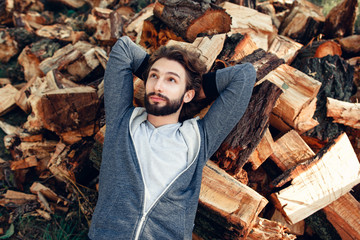 Man having rest on pile of wood top view. Young guy dreaming on bunch with firewood. Hard work, relax, handyman, country lifestyle concept
