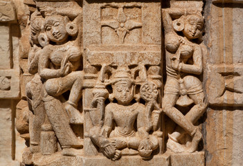 Dance of women near Lakshmi goddess on wall of traditional Hindu stone temple