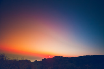 Obraz premium Beautiful summer landscape in the mountains with the sun at dawn. Colourful blue orange pink sky. Natural background