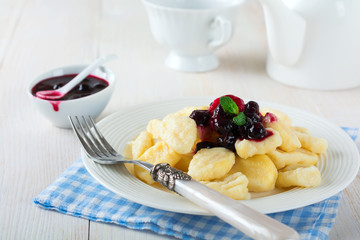 Cheese dumplings,gnocchi with sauce of black currants in a white ceramic plate for a healthy breakfast. Selective focus.