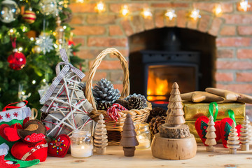 Diy Christmas: wooden toys, felt decorations, presents on the table, Christmas tree and fireplace with burning fire on the background, selective focus