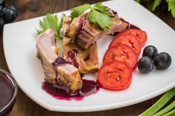 Smoked pork ribs with grape sauce, herbs and vegetables. Wooden background. Top view. Close-up