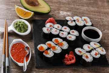 sushi rolls and ingredients served on a wooden surface