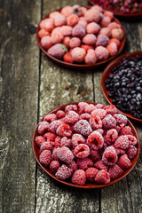 Frozen berries in bowls on wooden background. Selective focus.