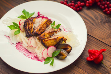 Duck breast with Chinese noodles, herbs and sauce. Wooden rustic table. Top view. Close-up