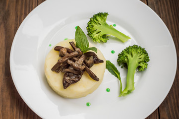 Mashed potatoes with mushrooms and boiled broccoli  sauce. Wooden background. Top view. Close-up