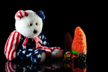 American teddy bear with ornaments on a festive Christmas tree.