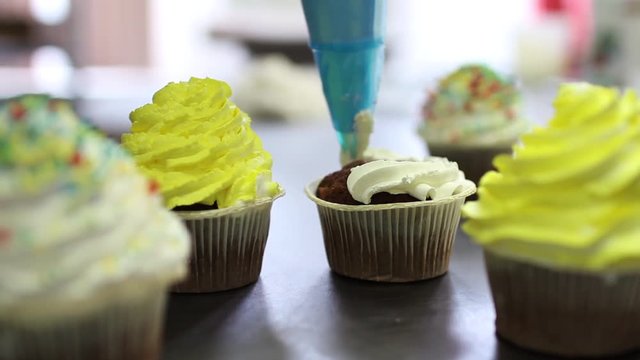 Decorating cupcake with cream. Culinary master class design cupcakes. Using cooking bag, confectioner making multicolor cupcakes for birthday party