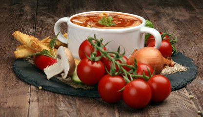 Tomato, red pepper soup, sauce with olive oil, rosemary and smoked paprika on a wooden background. 