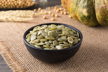 Green pumpkin seeds peeled in a black cup, snack for healthy and