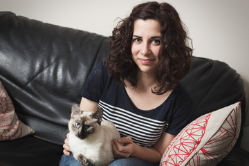Young female sitting on sofa with cat