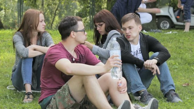 The company of friends on a picnic, guy drinking bottled water