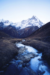 Fototapeta premium Stream with ice flowing down from the mountains, blue shade of t