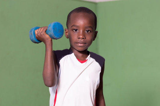 Child training to fitness in a gym by lifting weights.