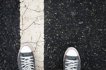 Top view of shoes and traffic line sign on street.