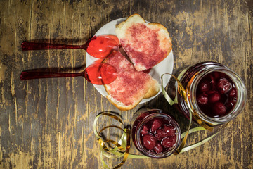 Cherry jam and white bread on wooden background