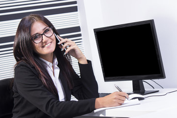 Young business woman making a call while in office.