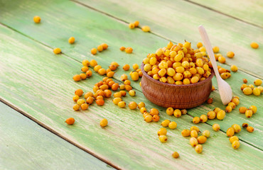 Sea buckthorn berries on a green wooden background