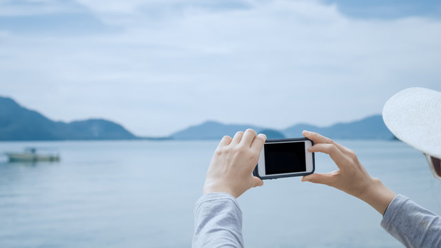 Copy space of woman hand using smart phone take photograph at beach background.
