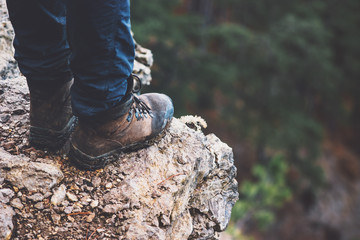 Feet boots on rocky cliff with forest aerial view Travel Lifestyle adventure vacations concept