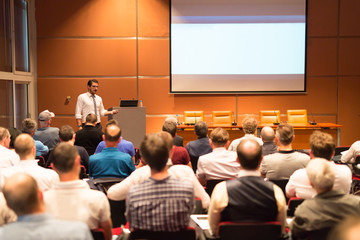 Speaker giving a talk in conference hall at business event. Audience at the conference hall. Business and Entrepreneurship.