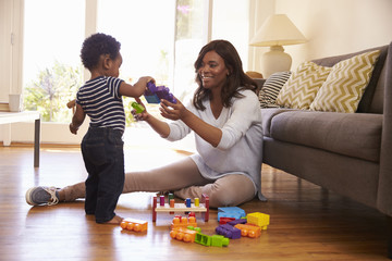 Mother And Son Playing With Toys On Floor At Home