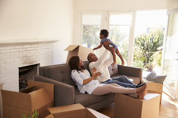 Parents Take A Break On Sofa With Son On Moving Day - obrazy, fototapety, plakaty