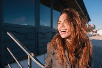 Happy woman in warm jacket on beach near cafe