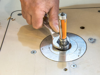 Carpenter setting CNC milling machine with a wrench.