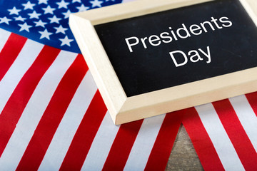 the text happy presidents day written in a chalkboard and a flag of the United States
