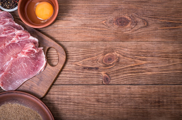 Fototapeta na wymiar Raw pork schnitzel with the ingredients . Concept of cooking.