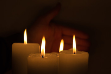 Fototapeta na wymiar hand behind burning candles