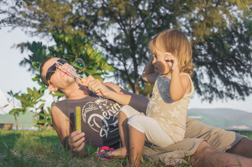 daddy and daughter blowing a bubbles in the park