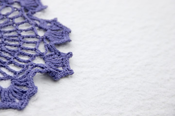 Element of purple knitted snowflakes on snow.