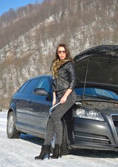 Beautiful young woman posing near a car in winter