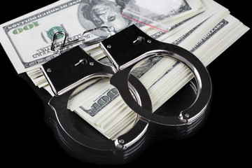 Handcuffs on stack of dollar banknotes and cocaine